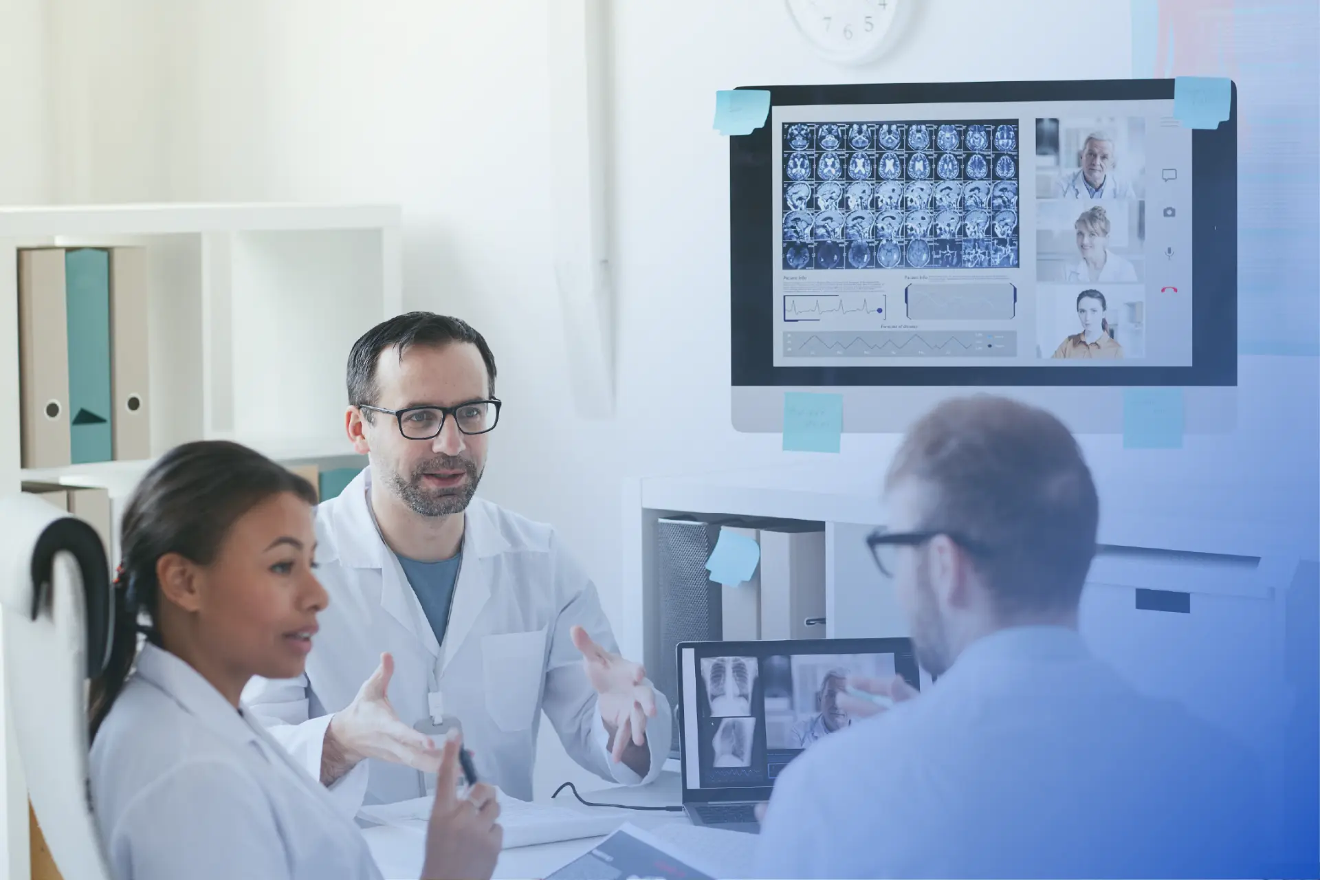 Clinicians reviewing medical scans and patient data on screens during a hospital consultation